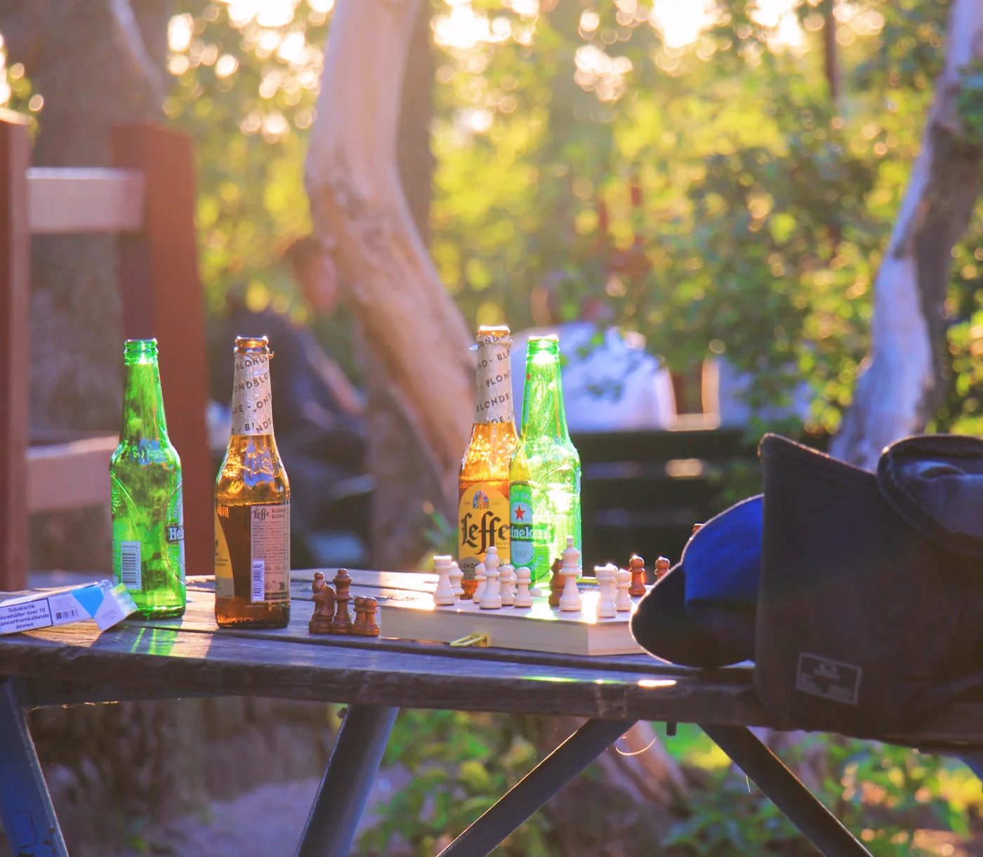 Bottles and a chess set on a small table in dappled sunlight